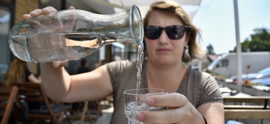 Žena nalieva vodu z fľaše počas horúceho dňa