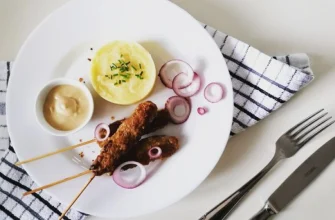 Pravé balkánske čevapčiči pripravené na grile s chrumkavým pita chlebom, ajvarom a čerstvou cibuľou.