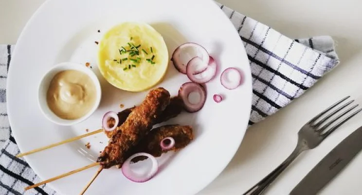 Pravé balkánske čevapčiči pripravené na grile s chrumkavým pita chlebom, ajvarom a čerstvou cibuľou.